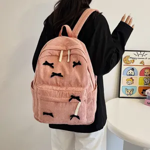 Pink corduroy backpack for women, cute school bag with black bow decor and multi pockets.