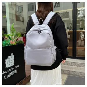 Detail lifestyle shot of a minimalist grey casual backpack worn outdoors, showcasing everyday use.