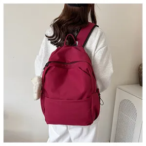 Detail shot of a stylish wine red casual backpack worn on model, showing large capacity daily use.