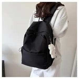 Detail view of casual black backpack with cute bear pendant, showing large capacity and design.