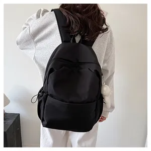 Detailed view of a casual black backpack worn on back, featuring large capacity and soft fabric.