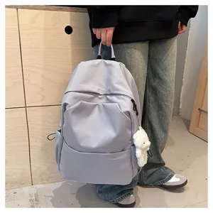 Detailed shot of minimalist solid color casual backpack with cute bear pendant and side pockets.