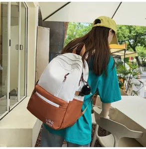 Detailed view of the stylish color-blocked school backpack worn outdoors in casual street setting.