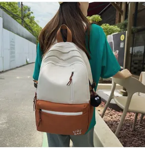 Detail view of a stylish color-blocking campus backpack in white and brown with front pocket.