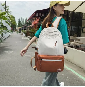 Two-tone canvas school backpack for women, stylish contrast color student daypack with cute charm.