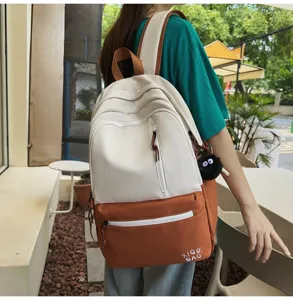 Stylish color-block canvas backpack detail, featuring multiple pockets and cute plush decor.
