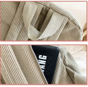 Corduroy backpack detail view featuring durable top handle and convenient zipper pocket design.