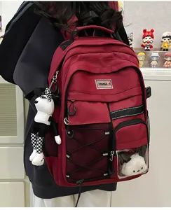 Large capacity utility backpack for students in dark red with multiple pockets and cute doll pendants.