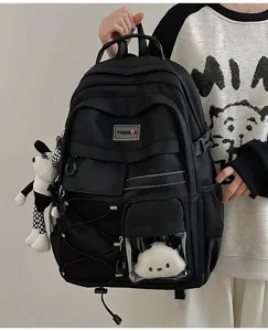 Detailed view of black utility style backpack with multiple pockets and cute plush doll pendant.
