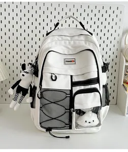 Workwear style student backpack with large capacity, mesh pockets, and cute doll charms.
