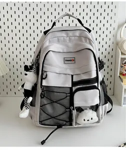 Detail view of utility style white school backpack with multi pockets and cute plush pendant.