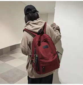 Detailed shot of the casual red canvas backpack showing its front pocket and brand patch.