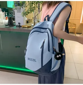 Large capacity school backpack for students, stylish dual-tone design with cute charm detail.
