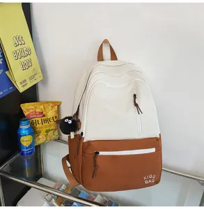 Detail view of the two-tone canvas backpack featuring convenient front zipper pockets and tags.