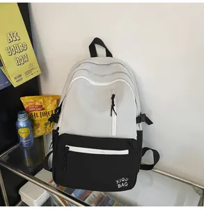 Detail view of the stylish contrast backpack featuring a front zipper pocket and clean design.