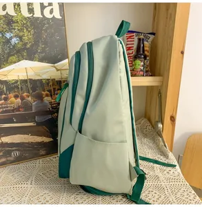 Sage green student backpack detail view, featuring dark green zippers and multi-pocket layout.