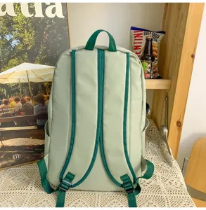 Detail view of the light green student backpack with dark green straps and functional design.