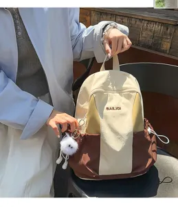 Detail view of the stylish casual color-block backpack featuring a cute fluffy plush pendant.