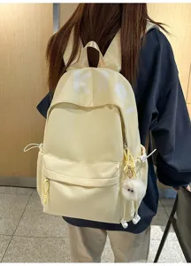 Close-up detail of the casual canvas backpack showing smooth zipper, side pocket and cute fluffy pendant.