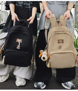 Detail view of large capacity campus school backpack with cute bear pendant and label.