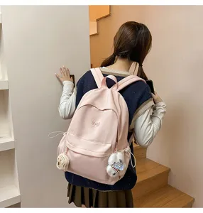 Pink school backpack detail view with cute plush pendants for casual campus lifestyle.