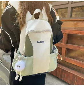 Casual contrast color backpack detail showing cute fluffy plush pendant and side drawstring.