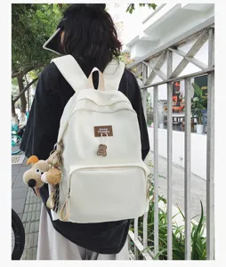 Detail view of the campus canvas backpack outdoors with cute bear pendant and clean pocket.