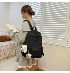 Detailed view of the casual black school backpack with cute plush pendants, ideal for daily use.