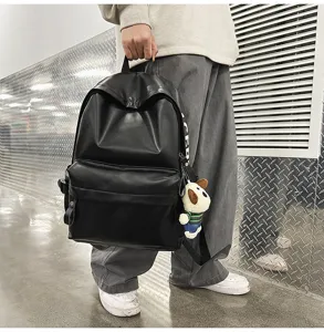 Black PU leather backpack for women, minimalist laptop school bag with front pocket design.