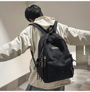 Detailed shot of a black minimalist school backpack worn on a model, casual everyday carry.