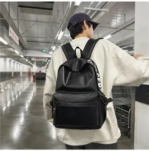 Lifestyle detail shot of a minimalist black PU leather backpack worn in an urban transit hall.