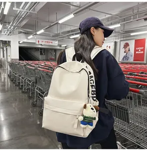 Detailed view of women's minimalist waterproof PU leather backpack in white with cute puppy pendant.