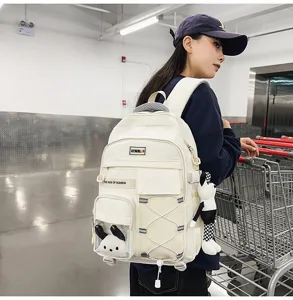 Detail view of large capacity beige school backpack worn by model in store aisle.