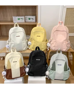 Casual multi-color campus backpack detail showcasing front pockets and furry keychain charm.