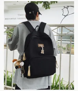 Detail view of casual black canvas school backpack with cute bear pendant and spacious design.