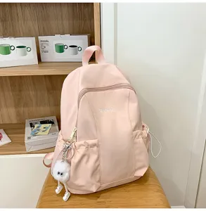 Pink lightweight waterproof backpack for women, casual school bag with cute fuzzy ball pendant.