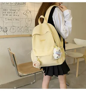 Detail view of the cute yellow canvas casual campus backpack with adorable plush toy pendants.