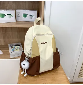 Detail shot of the two-tone canvas backpack with front pocket and cute plush pendant.
