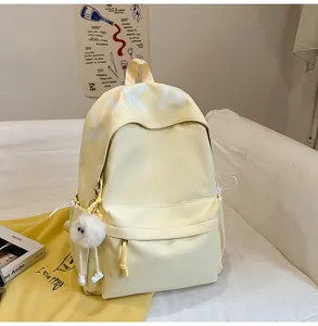 Detail view of large capacity yellow student backpack with cute plush pendant and Japanese style.