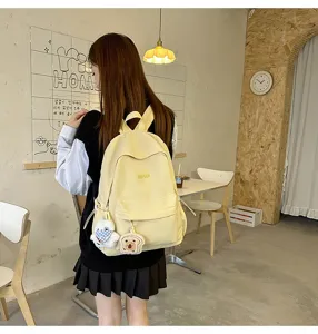 Close-up detail of a casual yellow campus backpack featuring cute plush pendants and pockets.