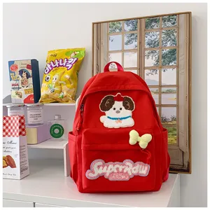 Cute red canvas school backpack with puppy embroidery patch and bow detail in lifestyle scene.