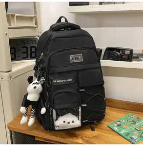 Black multi-pocket school backpack with clear window, cute doll pendant, and spacious design.