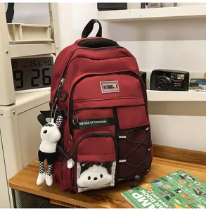 Red multi-pocket student backpack detail showing storage compartments and cute pendant.