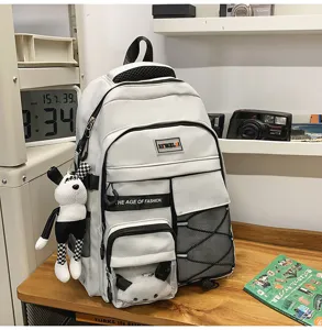 Detail view of white student backpack with multi-pockets, mesh design and cute plush pendant.