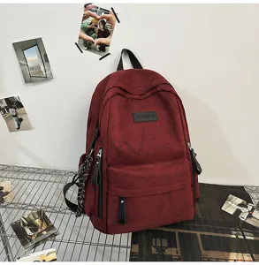 Detailed view of a dark red campus backpack with front pocket and metal wire shelf background.
