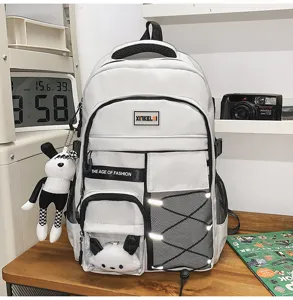 Detail view of a large capacity grey multi-pocket school backpack with cute doll pendant.