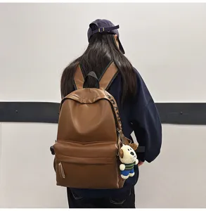 Brown PU leather casual backpack for women, stylish student school bag with cute dog pendant.