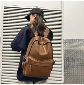 Detailed view of women's brown PU leather casual backpack in outdoor industrial setting.