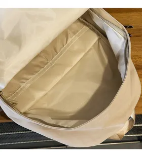 Beige backpack interior detail shot, showing large capacity main compartment and zipper pocket.