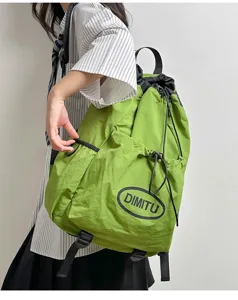Close-up detail shot of green drawstring backpack with front pocket and adjustable straps.